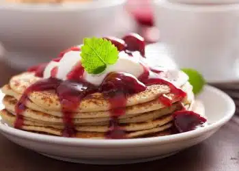 pancake con marmellata di ciliegie e yogurt serviti in un piatto