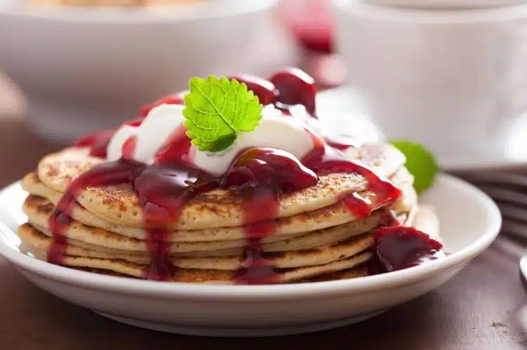 pancake con marmellata di ciliegie e yogurt serviti in un piatto